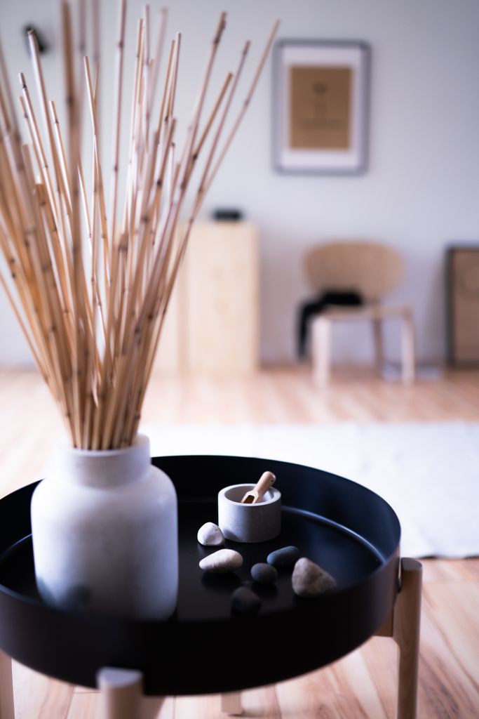 A modern Japandi-style interior featuring a round table with bamboo decor and a ceramic vase.