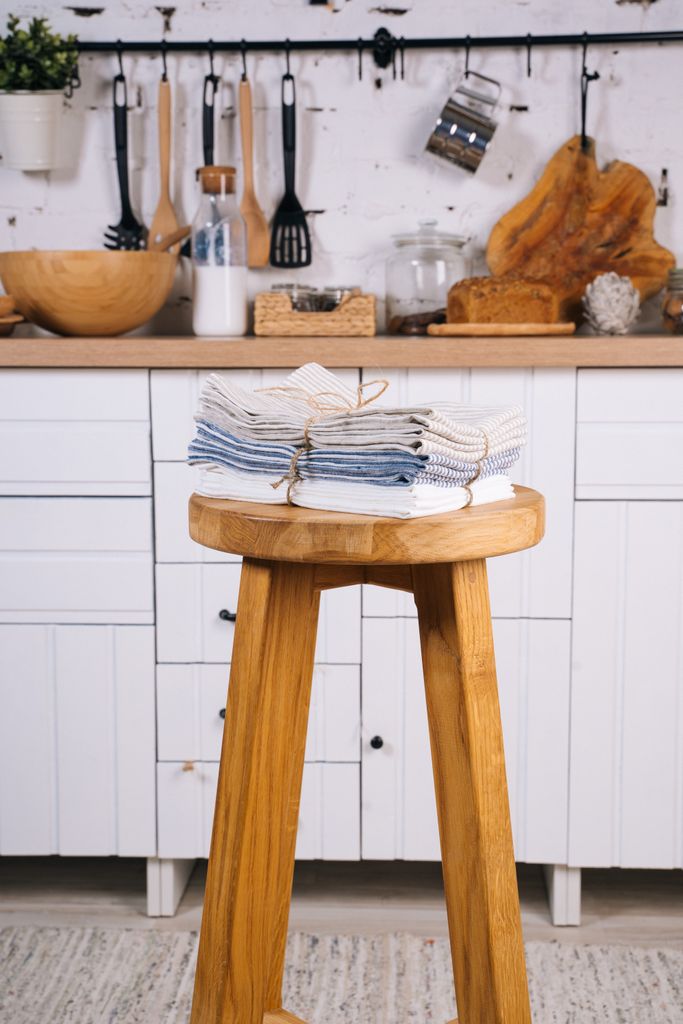 A warm kitchen setting with linens and wooden decor on a stool.