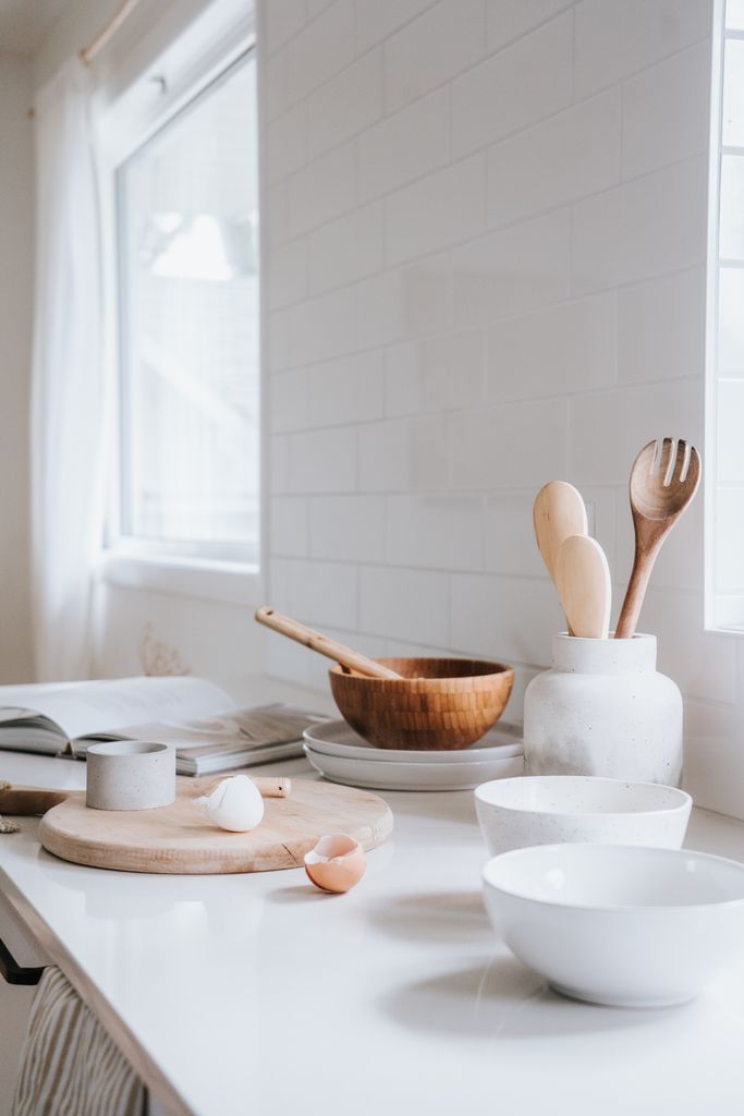 Bright, minimalist kitchen showcasing ceramic and wooden kitchenware on a countertop.