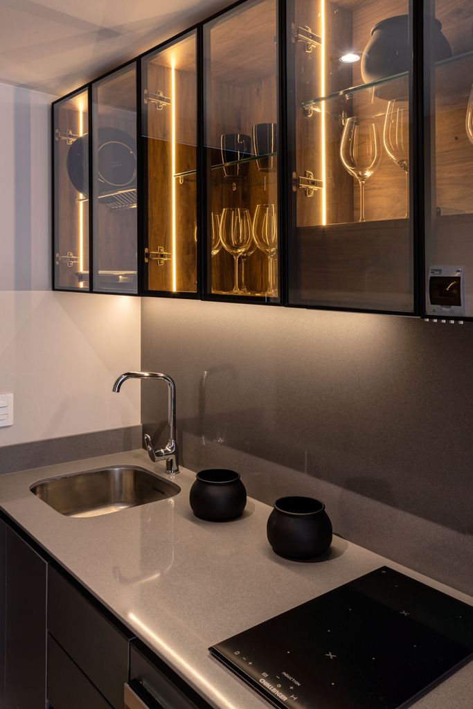 Elegant modern kitchen with illuminated glass cabinets and sleek countertops.
