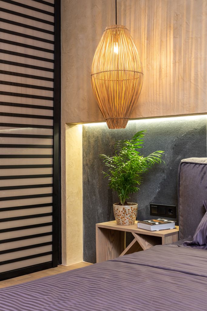 Stylish modern bedroom featuring a luxurious bed, elegant hanging light, and refreshing indoor plant decor.