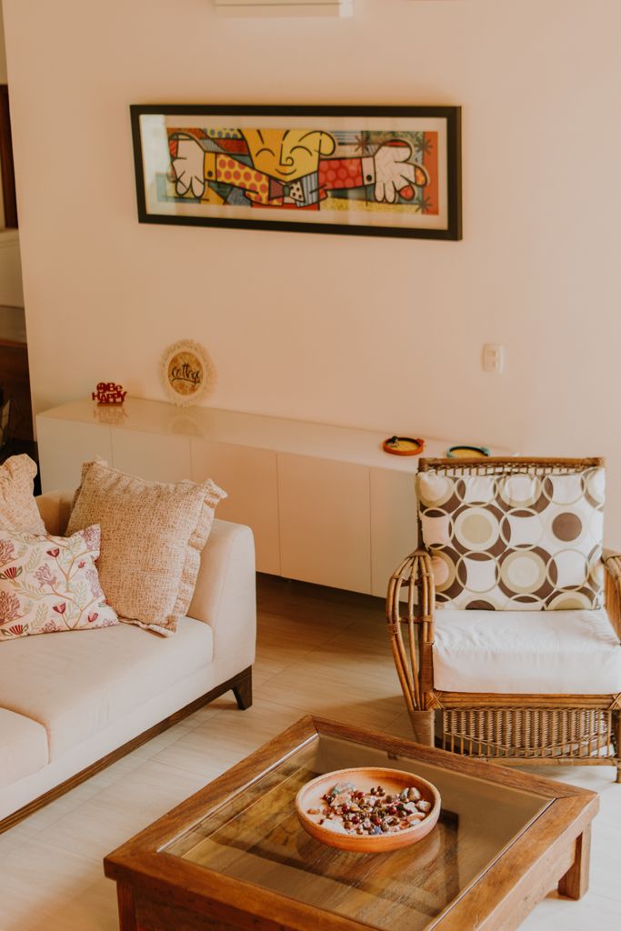 Warm and inviting living room with modern art, rattan chair, and sofa.